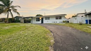 A single-story house with a front porch, a driveway, and a small lawn. - Modern King Suite Cozy Sofa Bed Near Everything (Pembroke Pines)