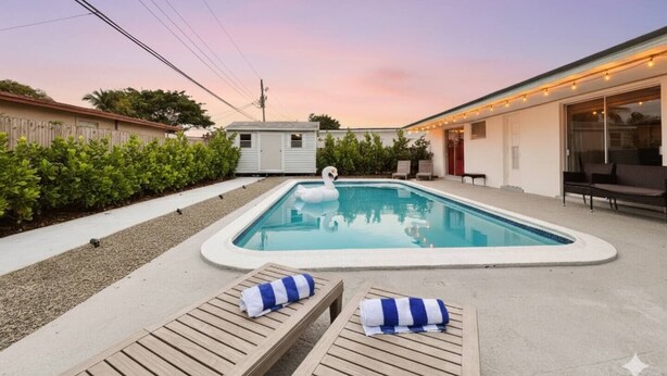 A swimming pool with lounge chairs and a swan float. - Modern King Suite Cozy Sofa Bed Near Everything (Pembroke Pines)