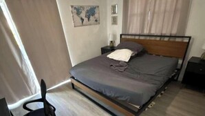 A bedroom with a bed, a chair, a nightstand, and a map on the wall. - Modern King Suite Cozy Sofa Bed Near Everything (Pembroke Pines)