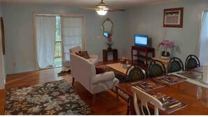 Un salon comprenant un canapé, une table à manger avec des chaises, un ventilateur de plafond et un téléviseur.