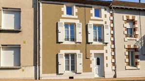 Un edificio con varias ventanas, algunas con contraventanas, y una puerta visible.