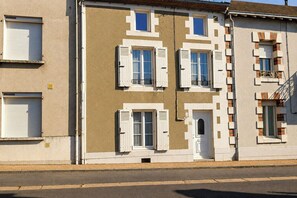 Ein Gebäude mit mehreren Fenstern, einige mit Fensterläden, und einer sichtbaren Tür.