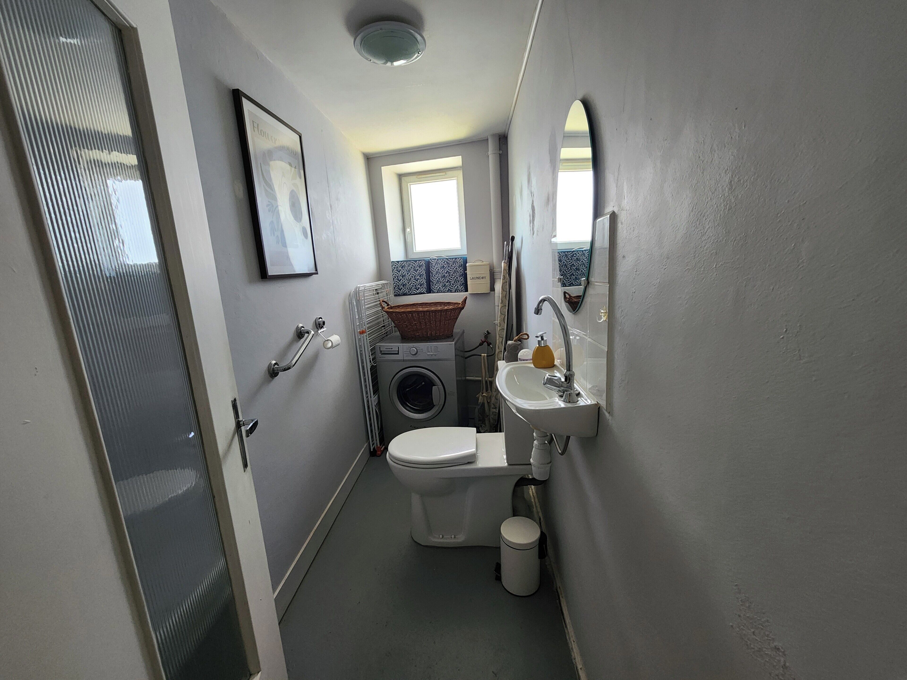 A compact bathroom with a toilet, washing machine, and sink.