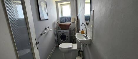 A compact bathroom with a toilet, washing machine, and sink.