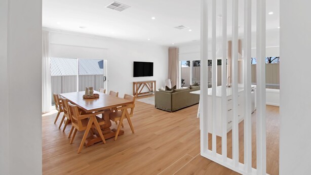 A modern living room with a wooden dining table, a sofa, and a TV mounted on the wall. - The Whitehaus. Contemporary Calm. Wagga Wagga. (Gobbagombalin)
