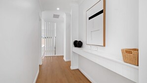 A hallway with white walls, wooden flooring, a white railing, and a framed picture on the wall. - The Whitehaus. Contemporary Calm. Wagga Wagga. (Gobbagombalin)