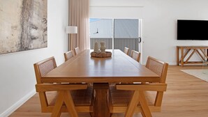 A modern dining room with a wooden table and chairs, a large abstract painting on the wall, and a TV on a stand. - The Whitehaus. Contemporary Calm. Wagga Wagga. (Gobbagombalin)