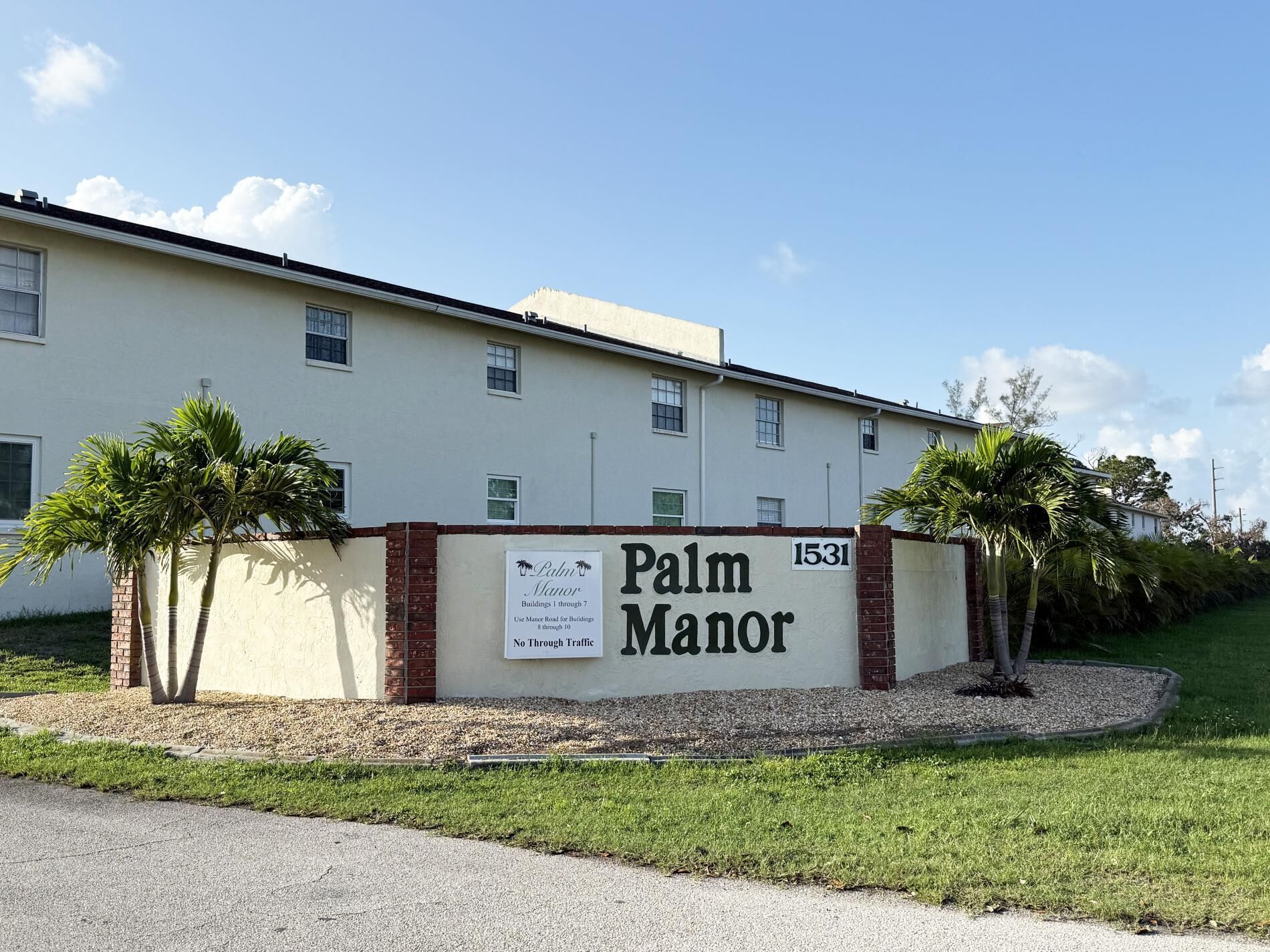 Een gebouw met de naam 'Palm Manor', met een bord waarop staat dat het een motel is.