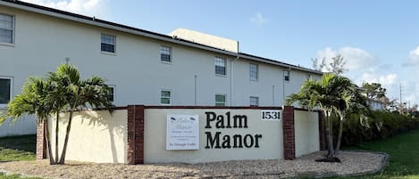 Een gebouw met de naam 'Palm Manor', met een bord waarop staat dat het een motel is.