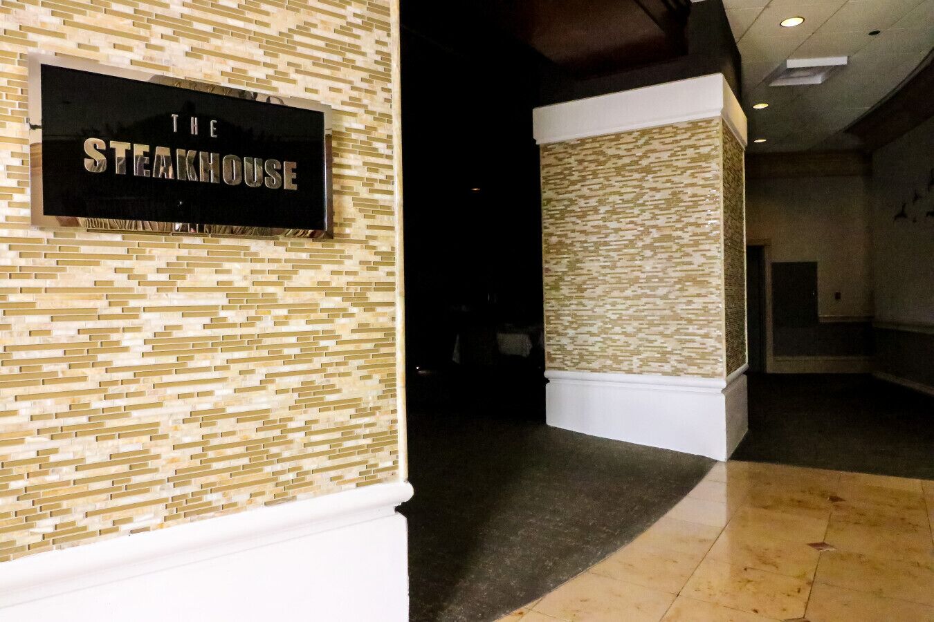 Eine Lobby mit einem Schild, auf dem "The Steakhouse" steht, und einer Wand mit Muster.