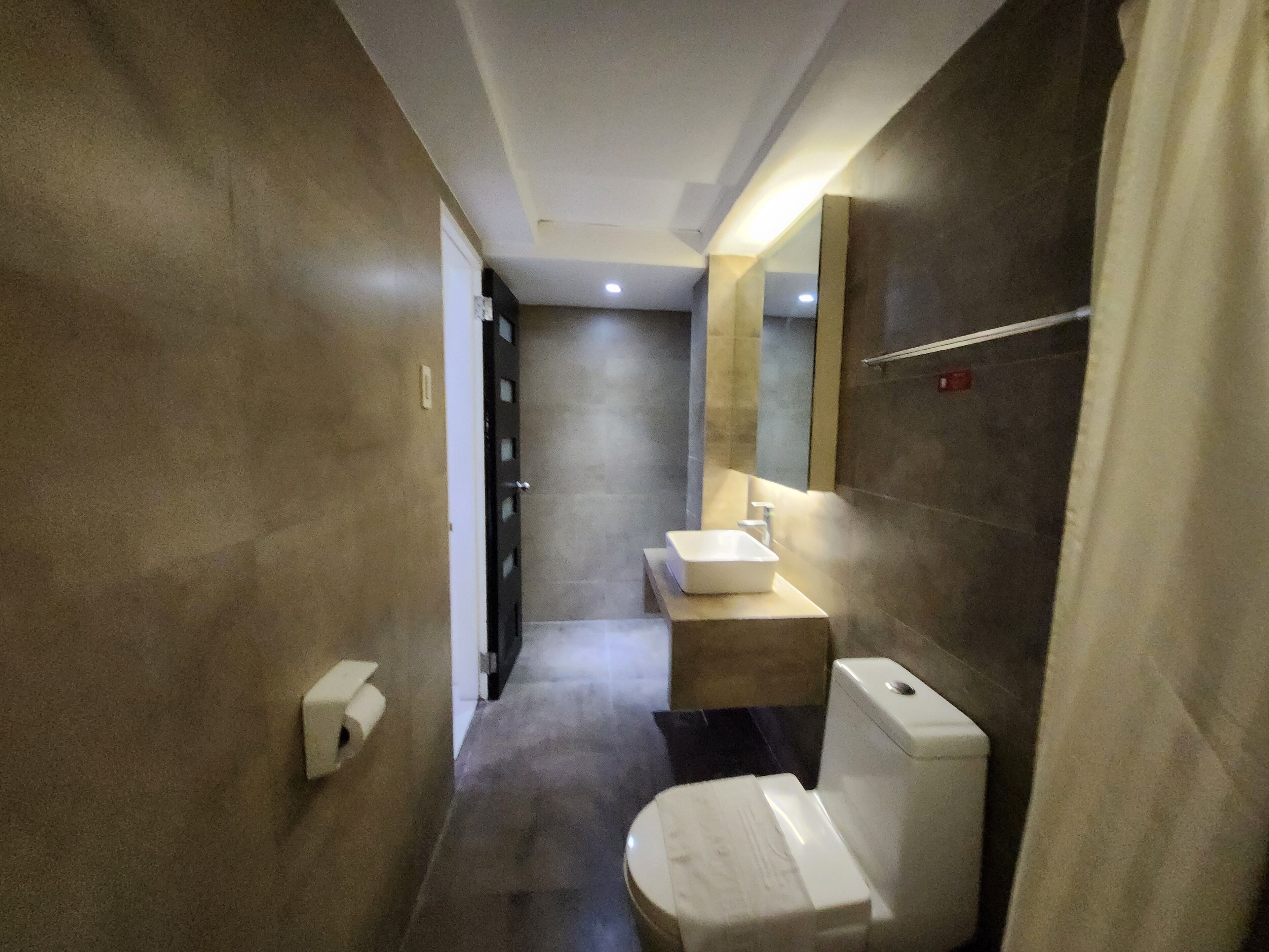 A modern bathroom with a toilet, sink, and mirror.