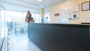 A reception area with a dark reception desk, a Christmas tree, and a whiteboard with notes.