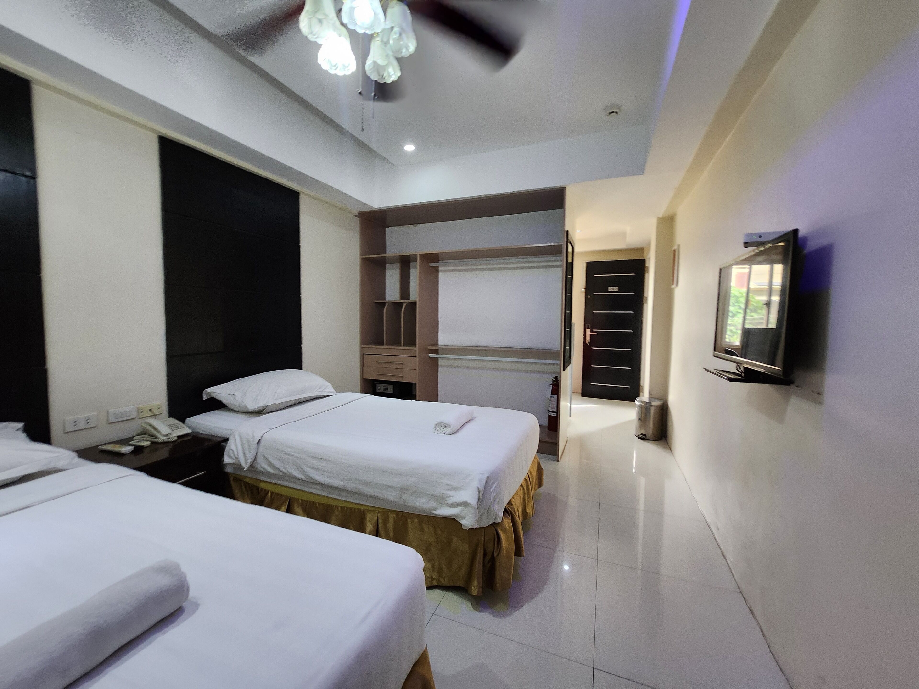 Une chambre d’hôtel avec deux lits, un bureau, un téléphone, une télévision et une armoire.