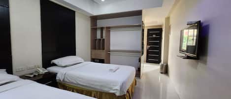 Une chambre d’hôtel avec deux lits, un bureau, un téléphone, une télévision et une armoire.