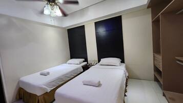A hotel room with two single beds, a ceiling fan, and a wardrobe.