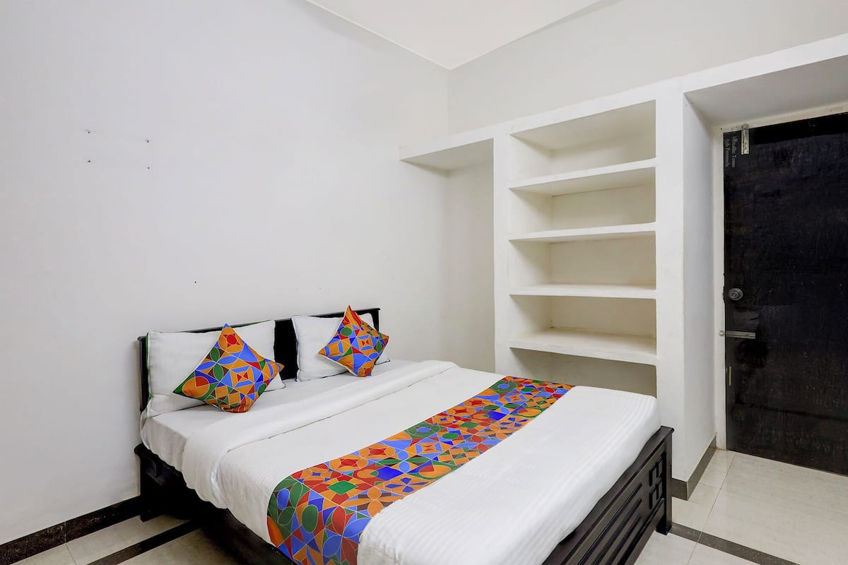 A bedroom with a bed, two pillows, a colorful bedspread, and built-in shelving.