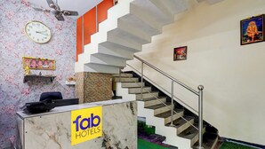 A hotel reception area with a marble counter, a clock, and a staircase. - Fabhotel Ravana Kottai (Chennai)