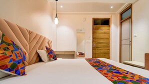 A hotel room with a large bed, a wooden wardrobe, a mirror, and a hanging light fixture. - Via Ashirwad (Lucknow)