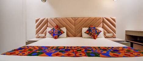 Un dormitorio moderno con una cama grande, dos almohadas, una colcha de estampado geométrico y dos lámparas colgantes.