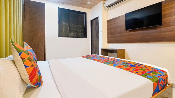 A hotel room with a bed, a TV mounted on the wall, and an air conditioning unit. - Fabhotel B Town (Mumbai)