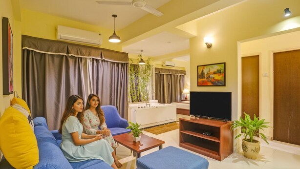 A living room with a sofa, a coffee table, a TV, and a potted plant. - Fabhotel Charvi Reemz (Anjuna)