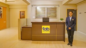 A hotel reception desk with a logo, a ceiling fan, and a framed artwork on the wall. - Fabhotel Charvi Reemz (Anjuna)