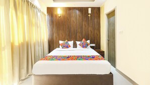 A hotel room with a bed, curtains, a wooden panel wall, and a nightstand. - Fabhotel Outstay (Navi Mumbai)