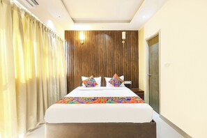 A hotel room with a bed, curtains, a wooden panel wall, and a nightstand. - Fabhotel Outstay (Navi Mumbai)