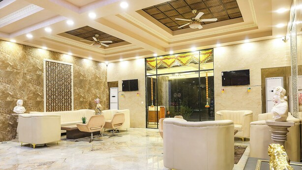 A hotel lobby with marble flooring, a seating area with sofas, a reception desk, and a ceiling fan. - Fabhotel Outstay (Navi Mumbai)