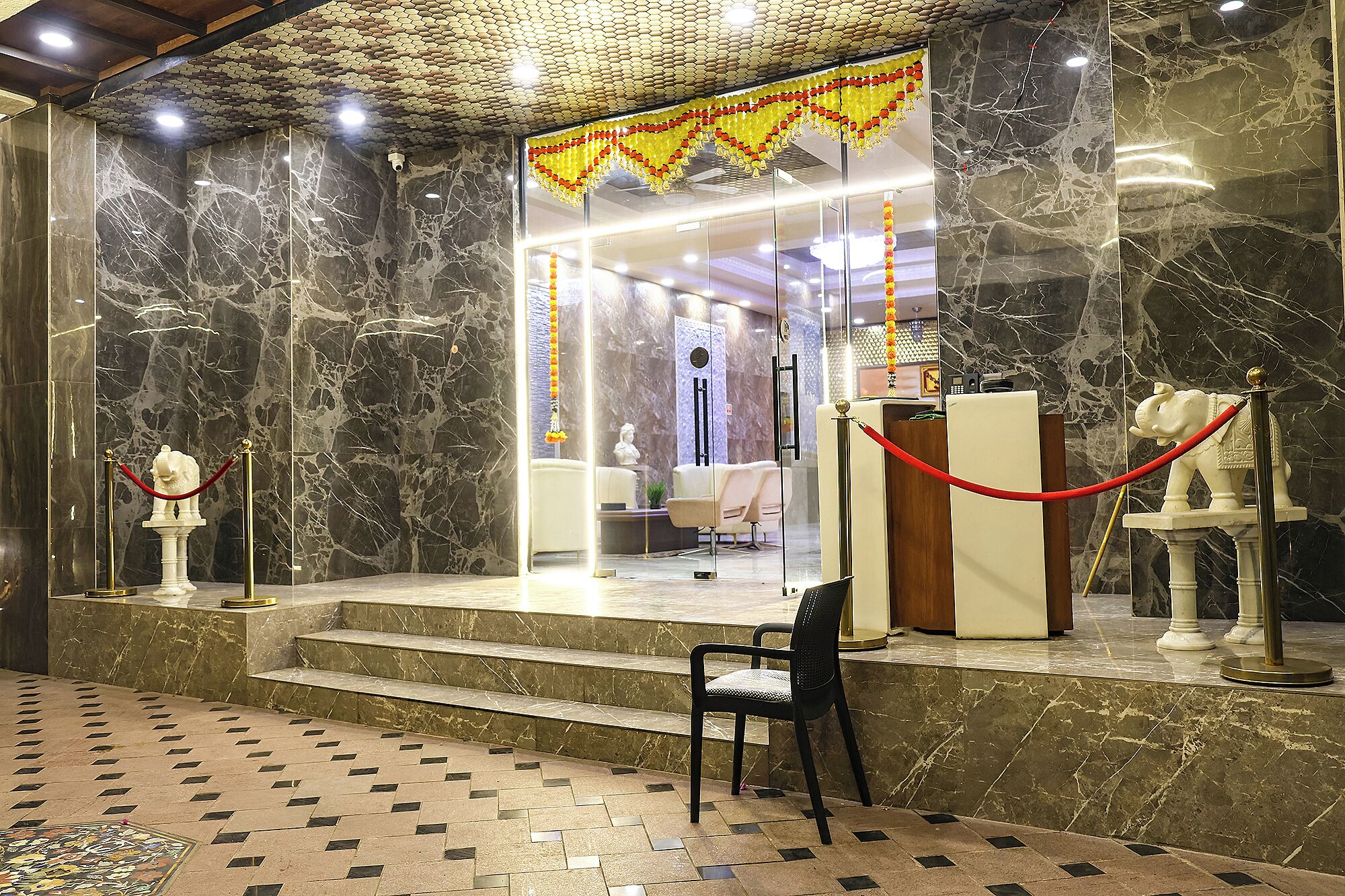 A lobby with marble walls, a reception desk, a waiting area with chairs, and a statue.