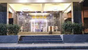 A hotel entrance with marble steps, a reception desk, and a red rope barrier. - Fabhotel Outstay (Navi Mumbai)
