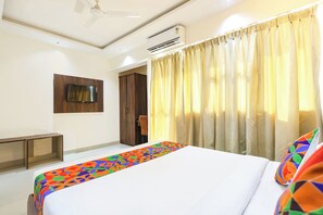 A hotel room with a bed, a TV mounted on the wall, an air conditioning unit, and a window with curtains. - Fabhotel Outstay (Navi Mumbai)