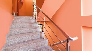 A staircase with granite steps, metal handrails, and orange walls. - Via Capitol Square (Jaipur)