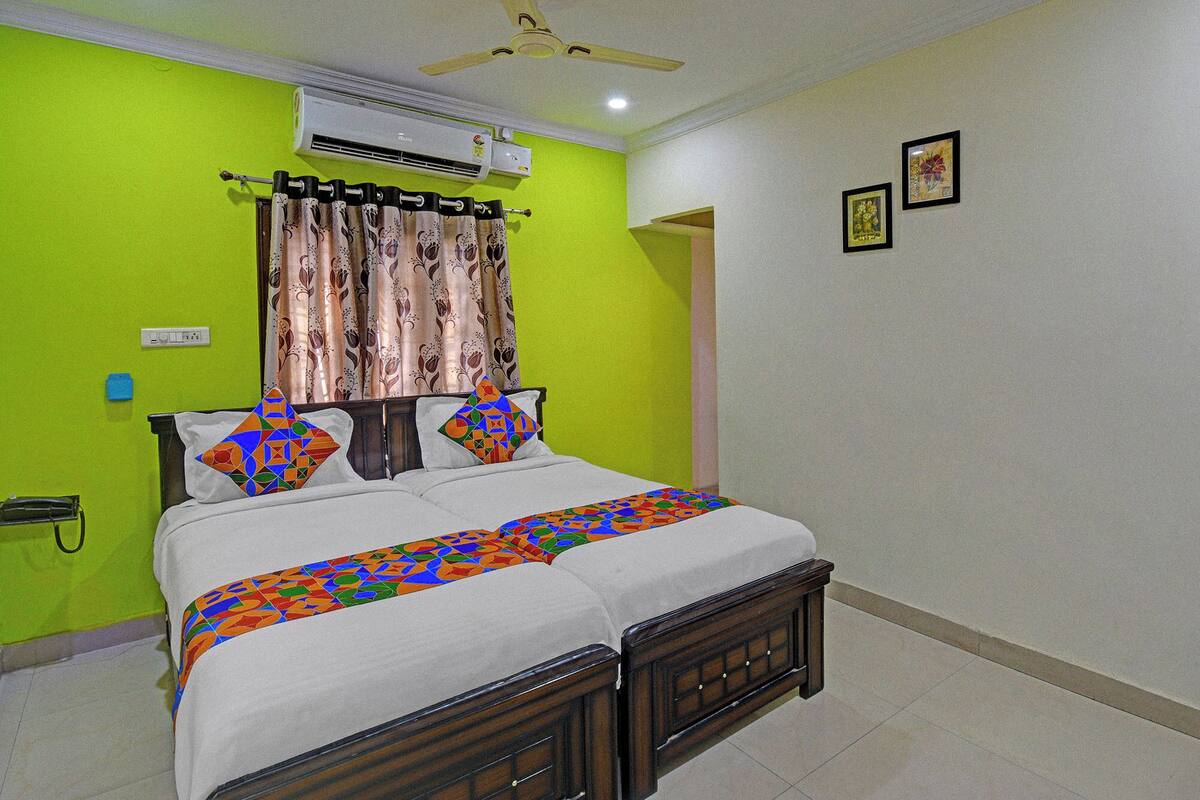 A bedroom with a bed, an air conditioner, a ceiling fan, and a green wall.