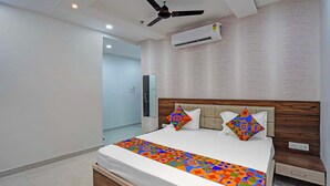 A modern hotel room with a bed, a ceiling fan, an air conditioning unit, and a wooden headboard. - Fabhotel Shri Vishwanath (Varanasi)