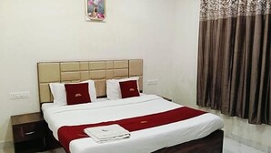 A hotel room with a bed, a nightstand, a red throw blanket, and a window with curtains. - Fabhotel Vedika (Kolkata)