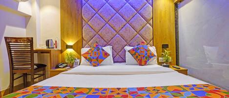 A hotel room with a large bed, a wooden headboard, a bedside table with a lamp, a chair, and a view of the outside.