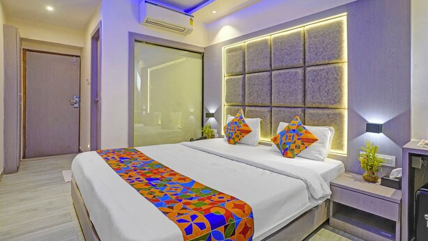 Ein modernes Hotelzimmer mit einem großen Bett, einem Nachttisch mit Lampe und einer wandmontierten Klimaanlage.