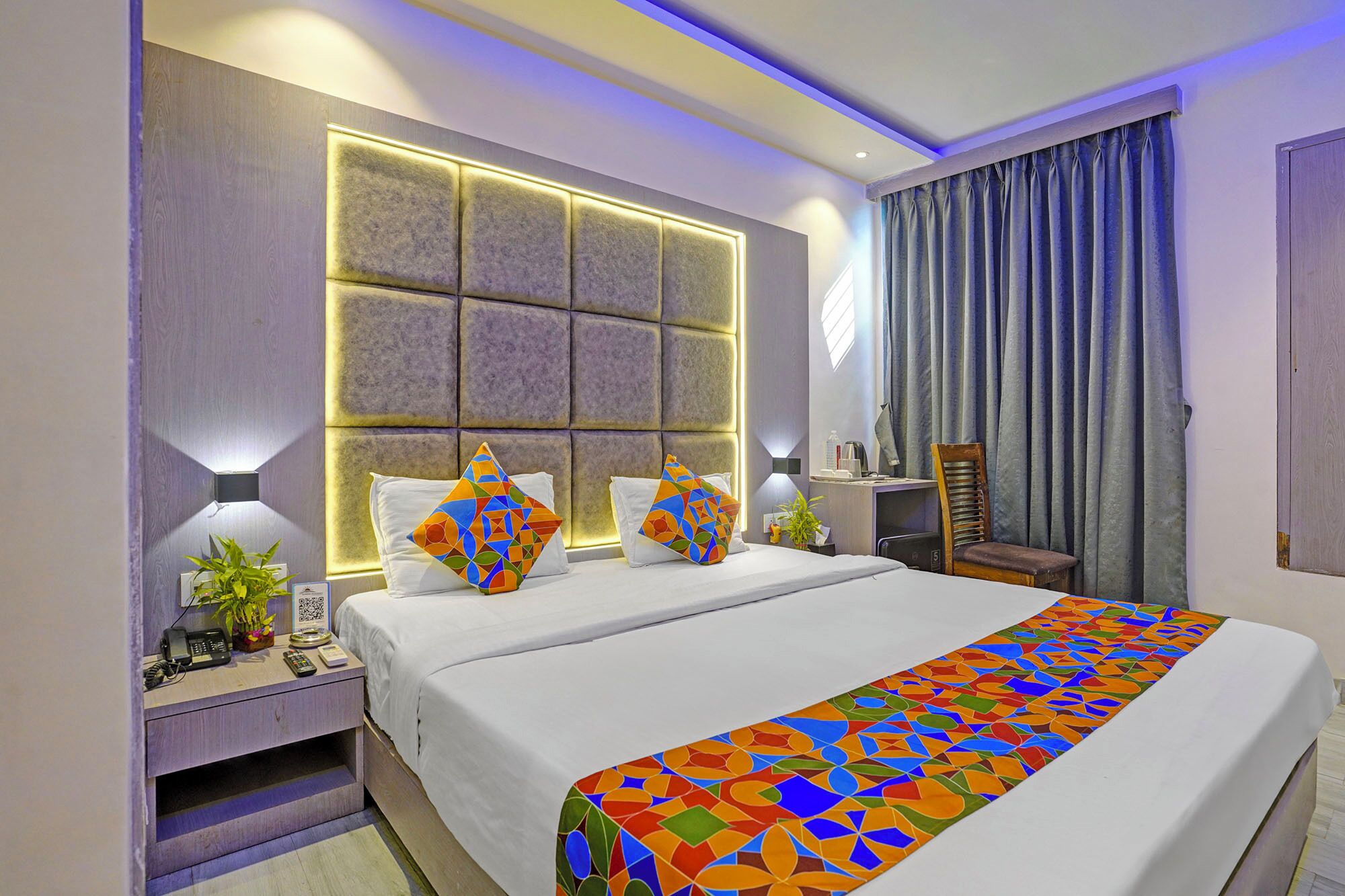 A modern hotel room with a large bed, two bedside tables, a desk, and a chair.