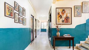 A hallway with art on the walls, a table with a vase and books, and a staircase on the right. - Via RK Exclusive (Hinjawadi)