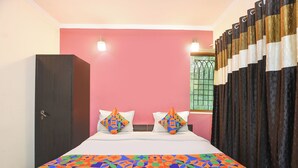 A room with a bed, two pillows, a wardrobe, and a window with curtains. - Fabhotel Uk House Residency (Gurugram)