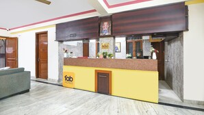 A reception desk with a 'fab hotels' sign, a reception area with a marble floor, and a ceiling fan. - Fabhotel Uk House Residency (Gurugram)