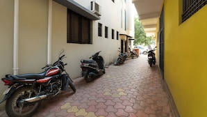 A narrow alley with tiled pavement, lined with parked motorcycles and scooters, and buildings with windows and shutters. - Fabhotel Ramraj Inn (Chhatrapati Sambhajinagar)