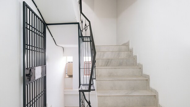 A staircase with a black metal railing and beige steps. - Fabhotel The Dream Inn (Faridabad)