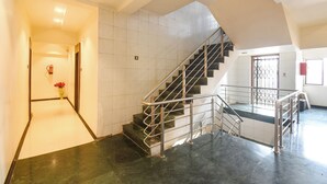 Un escalier avec des rampes en métal menant à l’étage supérieur, un mur recouvert de carreaux et une porte agrémentée d’un élément décoratif.