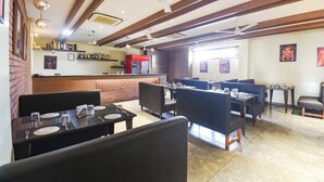 Un restaurant avec des banquettes et des tables, des poutres en bois au plafond et un mur en briques.