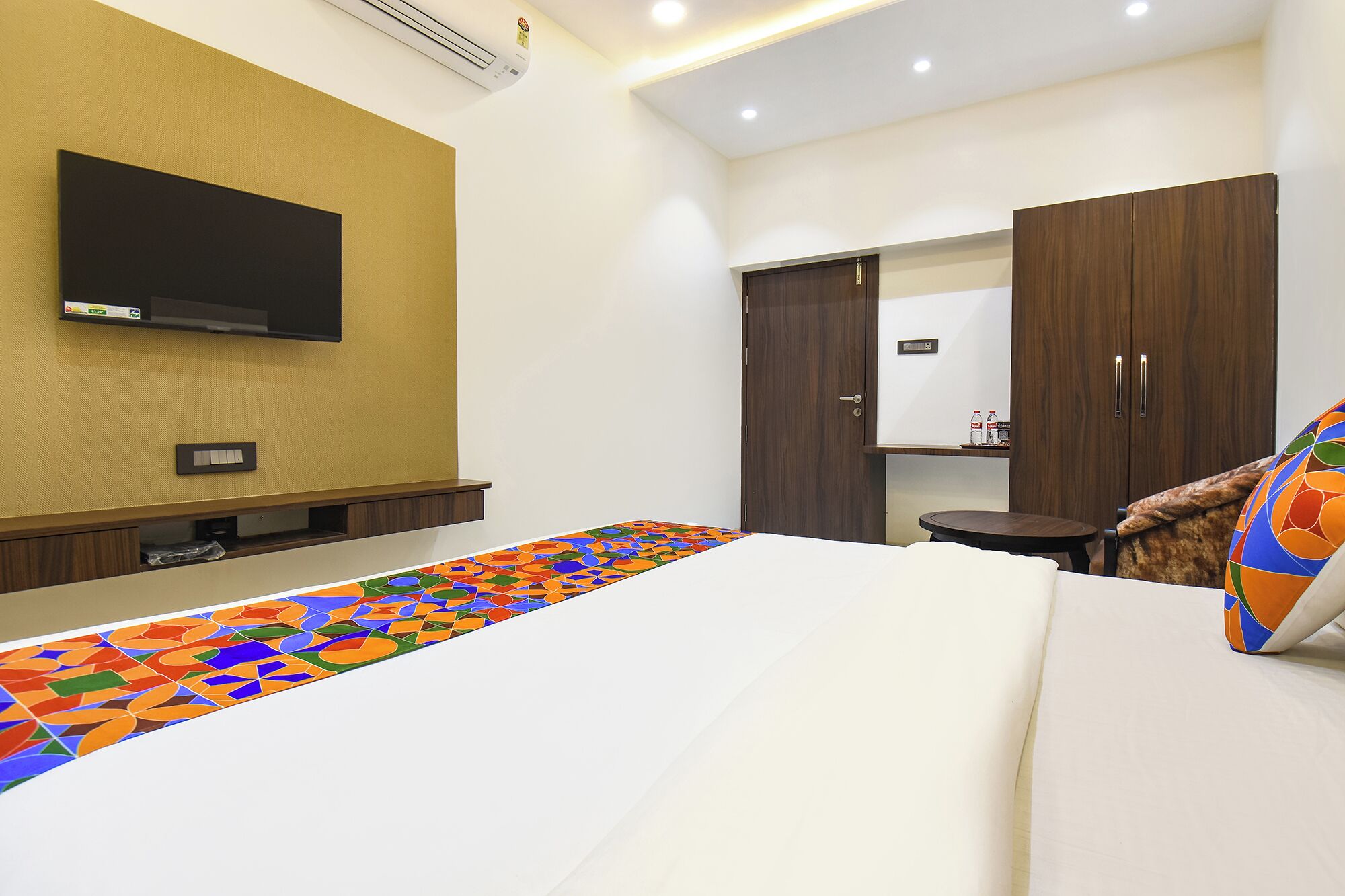 Une chambre d’hôtel avec un lit, un téléviseur fixé au mur, une armoire et une petite table.
