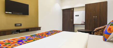 Une chambre d’hôtel avec un lit, un téléviseur fixé au mur, une armoire et une petite table.