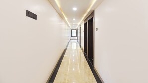 Un long couloir bien éclairé, doté d’un sol brillant, qui mène à une porte avec une fenêtre au bout.