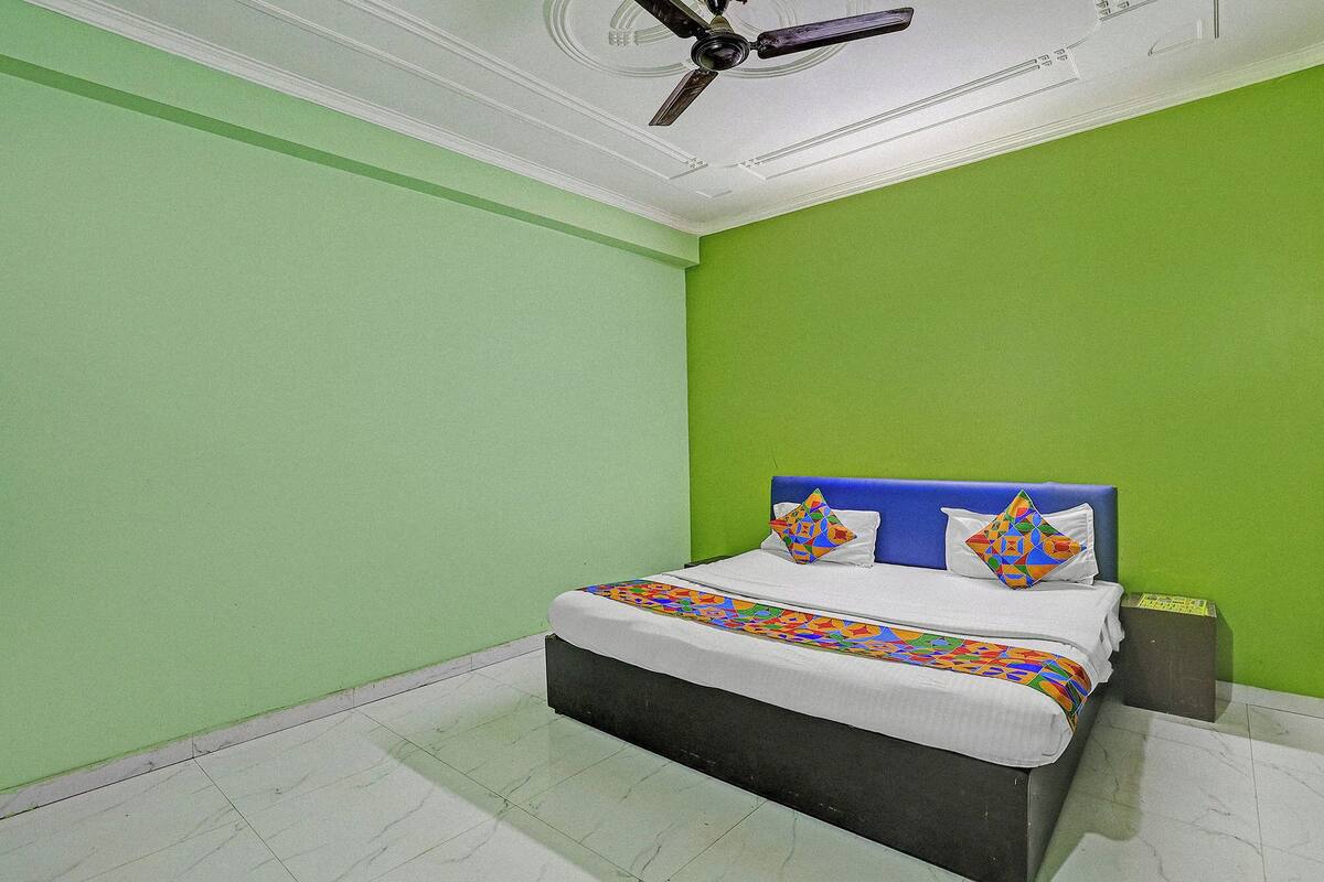 A bedroom with a bed, green walls, a ceiling fan, and a patterned bedspread.